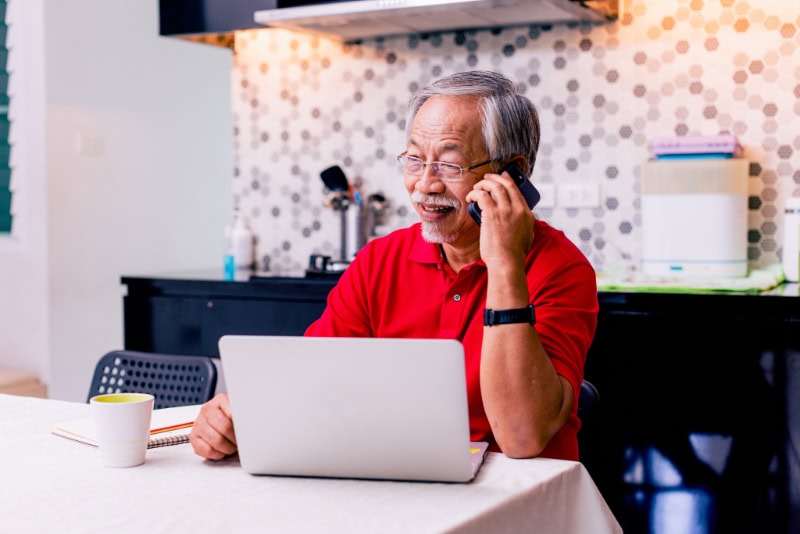 Senior talking on the phone at home in his kitchen.
